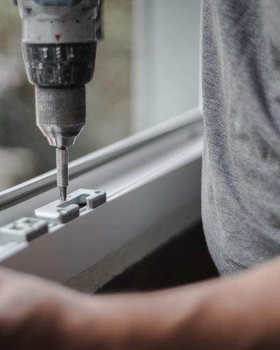 Caucasian man installs fittings for a window frame.